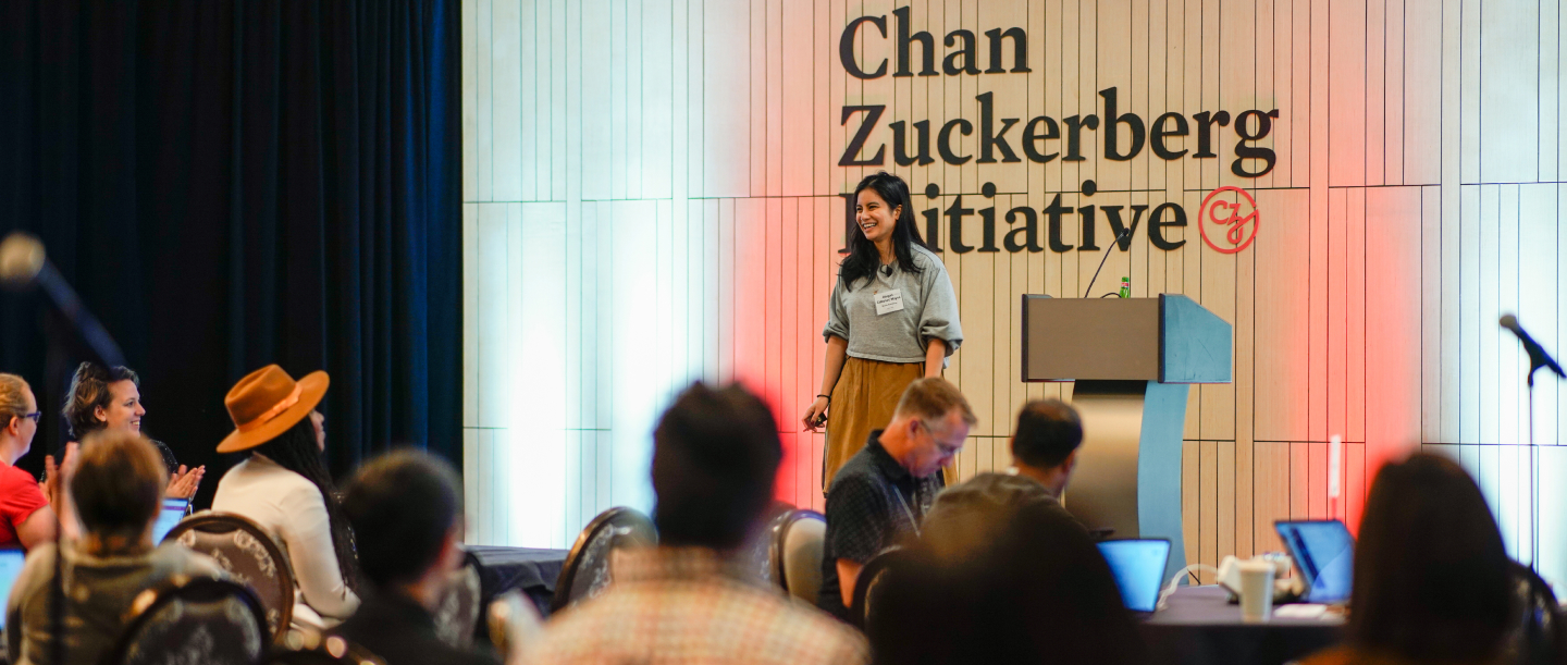 A speaker presents at a conference hosted by Chan Zuckerberg Initiative, with an engaged audience in a well-lit room.