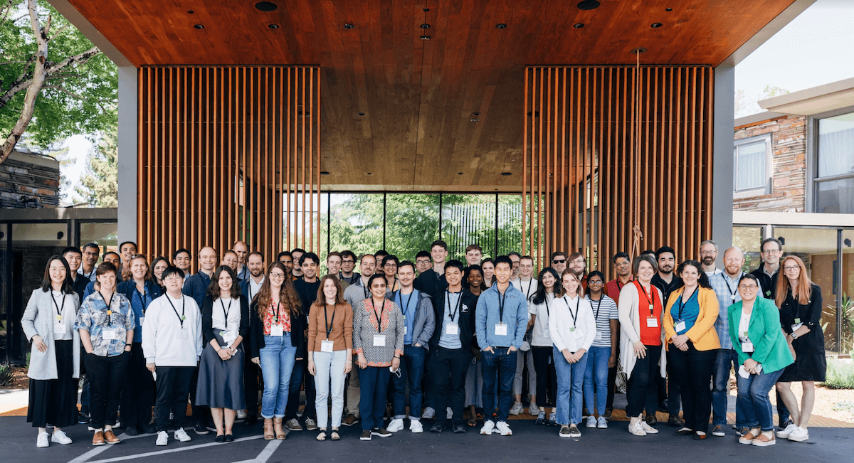 Workshop participants stand outside the meeting venue and smile for a group picture.