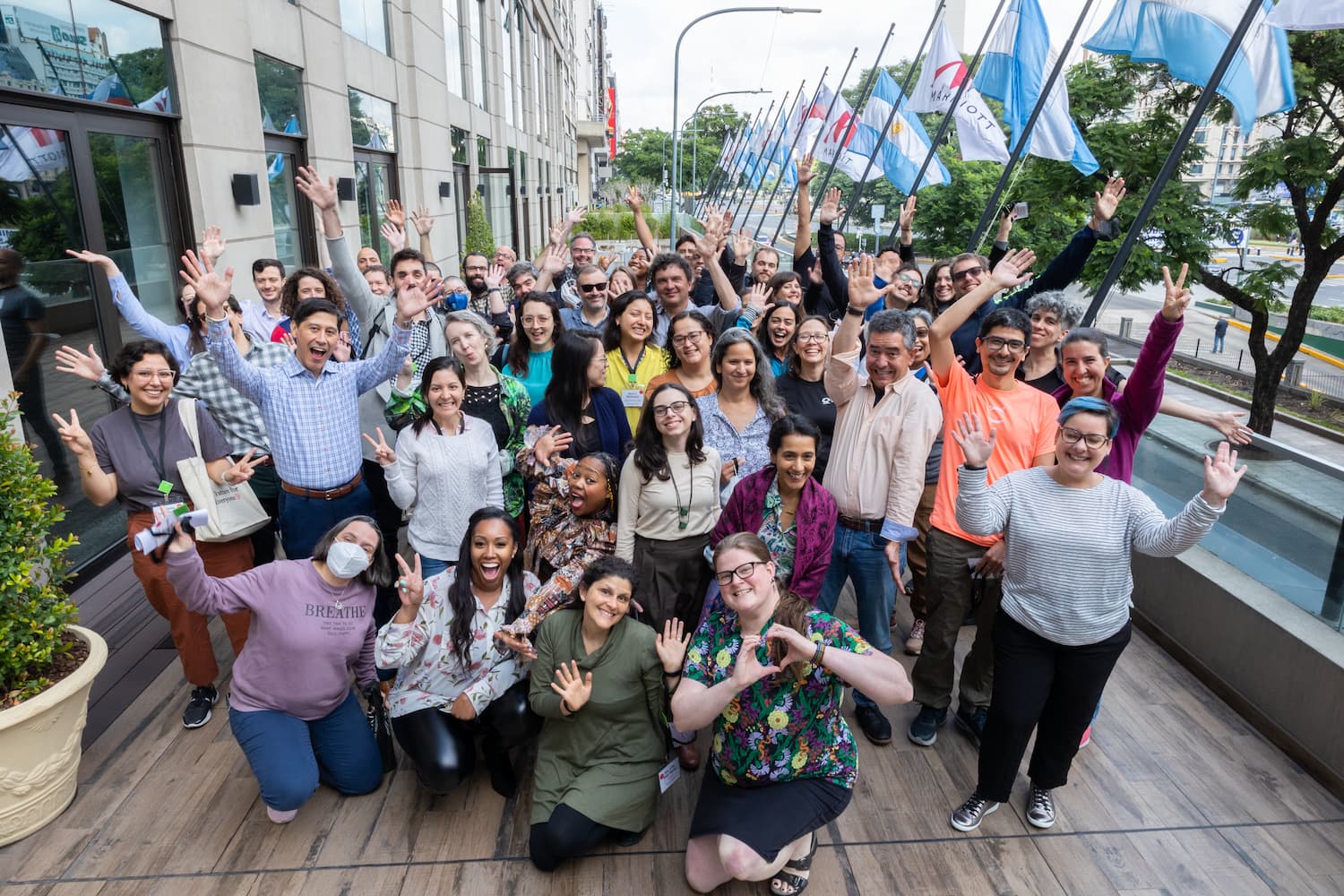 A group of participants at CZI’s Accelerating Open Science in Latin America Meeting wave to the camera on a balcony outside the meeting venue.