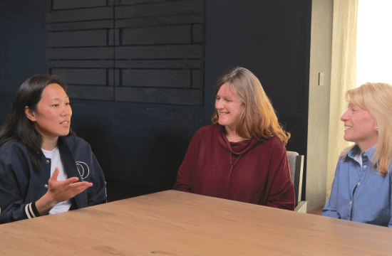 Three women seated at a table talking.