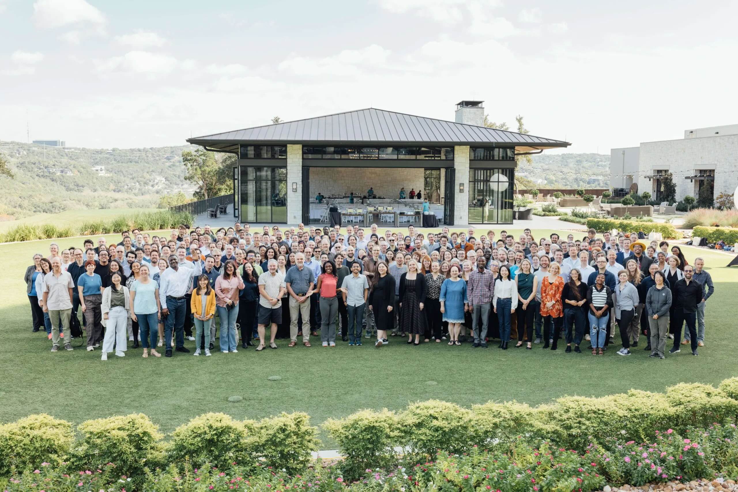 Participants of the Imaging the Future 2024: Life Illuminated meeting stand on the lawn of Omni Barton Creek Resort & Spa and look up to the camera.